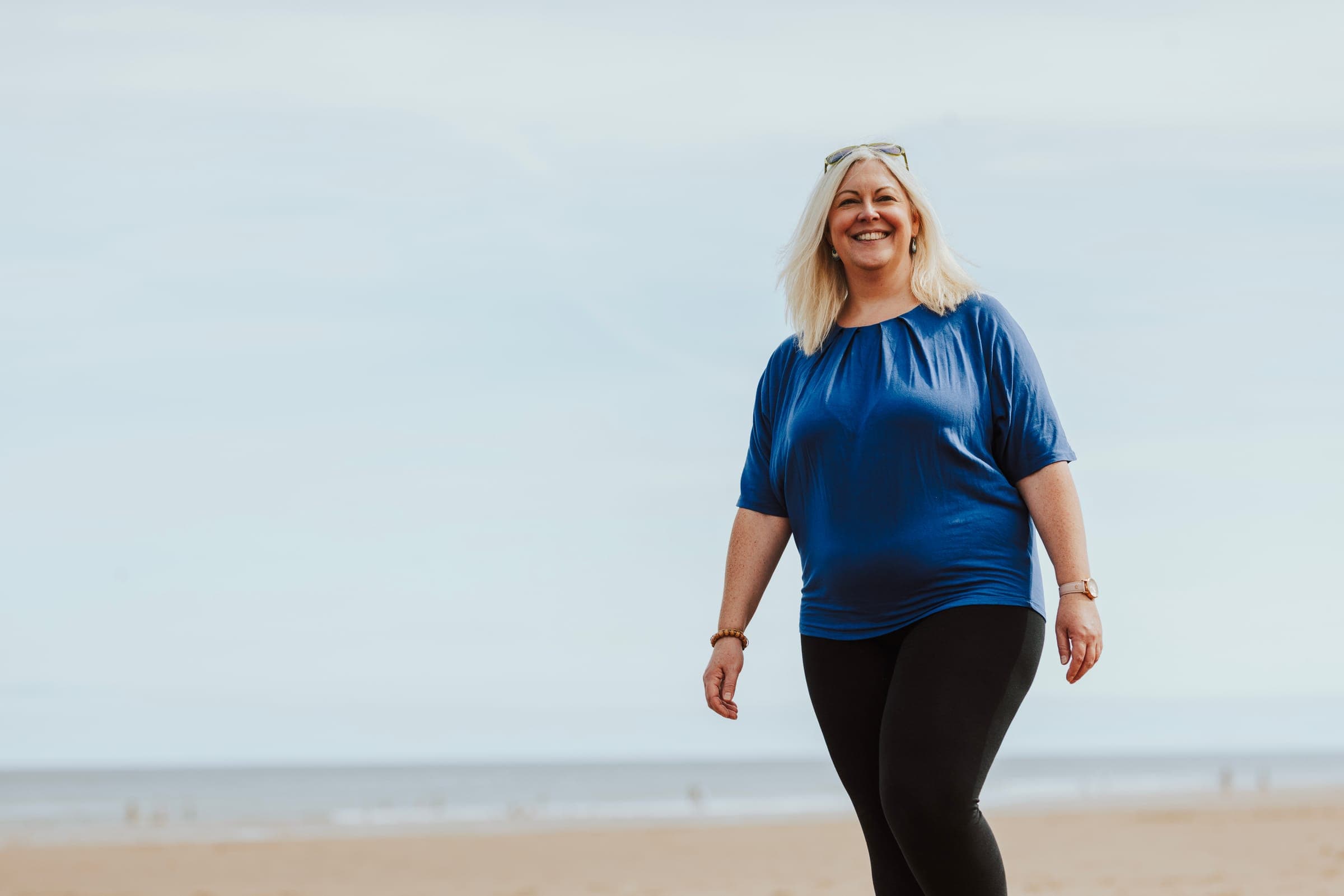 Dr Melanie Lee smiling as she walks along a sunlit beach