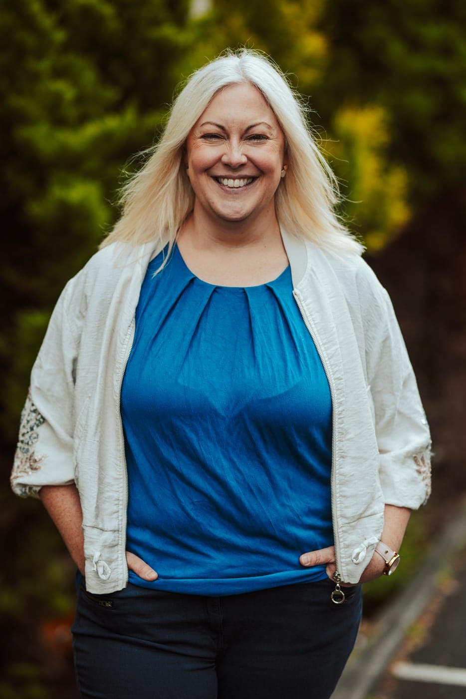 Dr Melanie Lee, smiling, standing outdoors in a white jacket